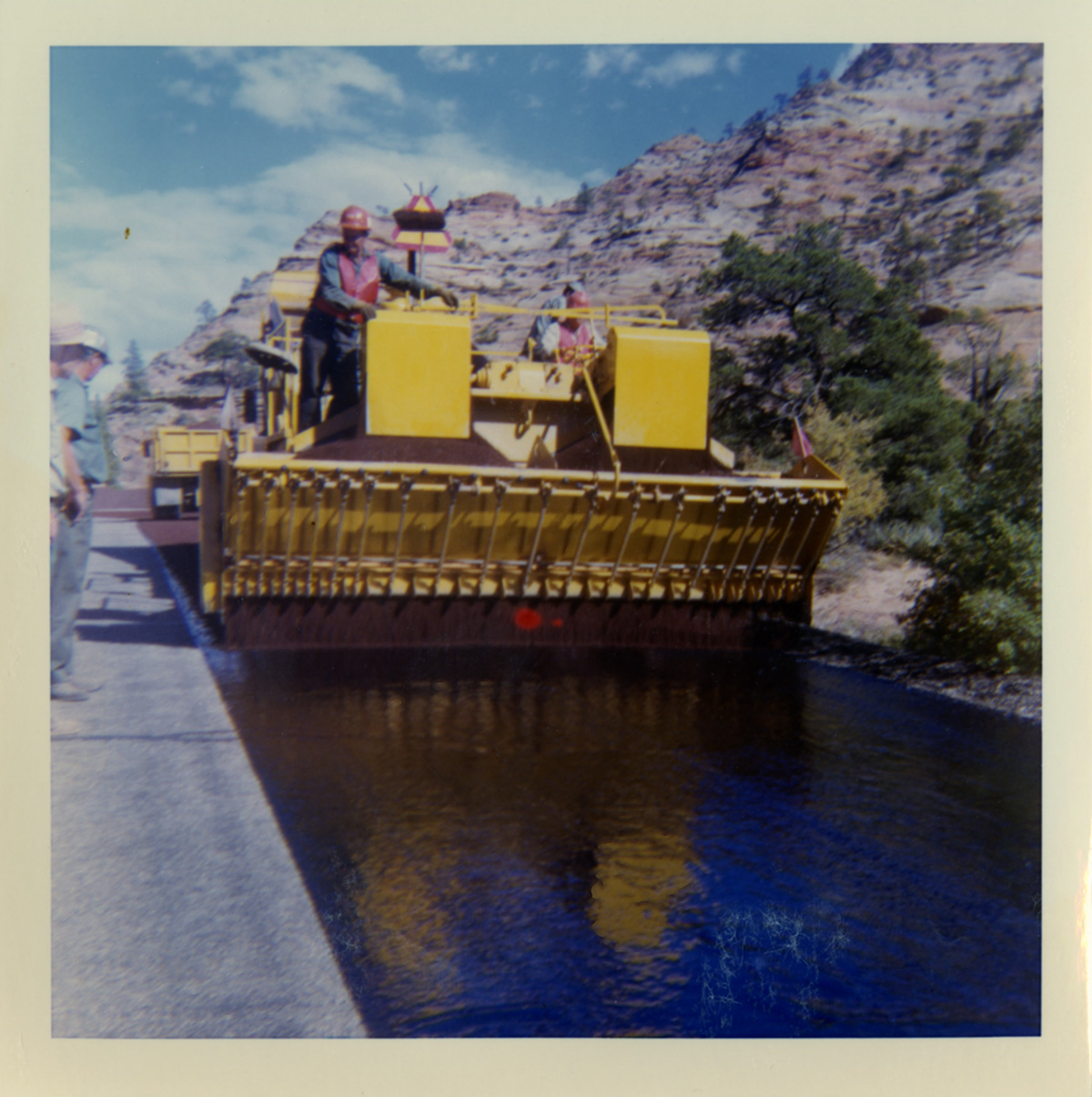 Men utilizing chipseal machine to chipseal the road.