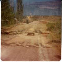 Men operating construction vehicles to clear rocks from road.