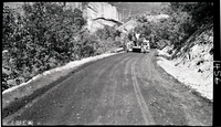 Workers engaged in experimental road paving of the floor of the valley road, smoothing the processed material to ready it for compaction.