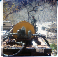 Man standing near sealcoating tank during road work.