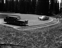 Man and woman stand near car parked in the newly constructed parking area at Chessman Ridge Overlook. National Park Service station wagon parked at left. Taken as a record of completed project. [No positive for this negative]