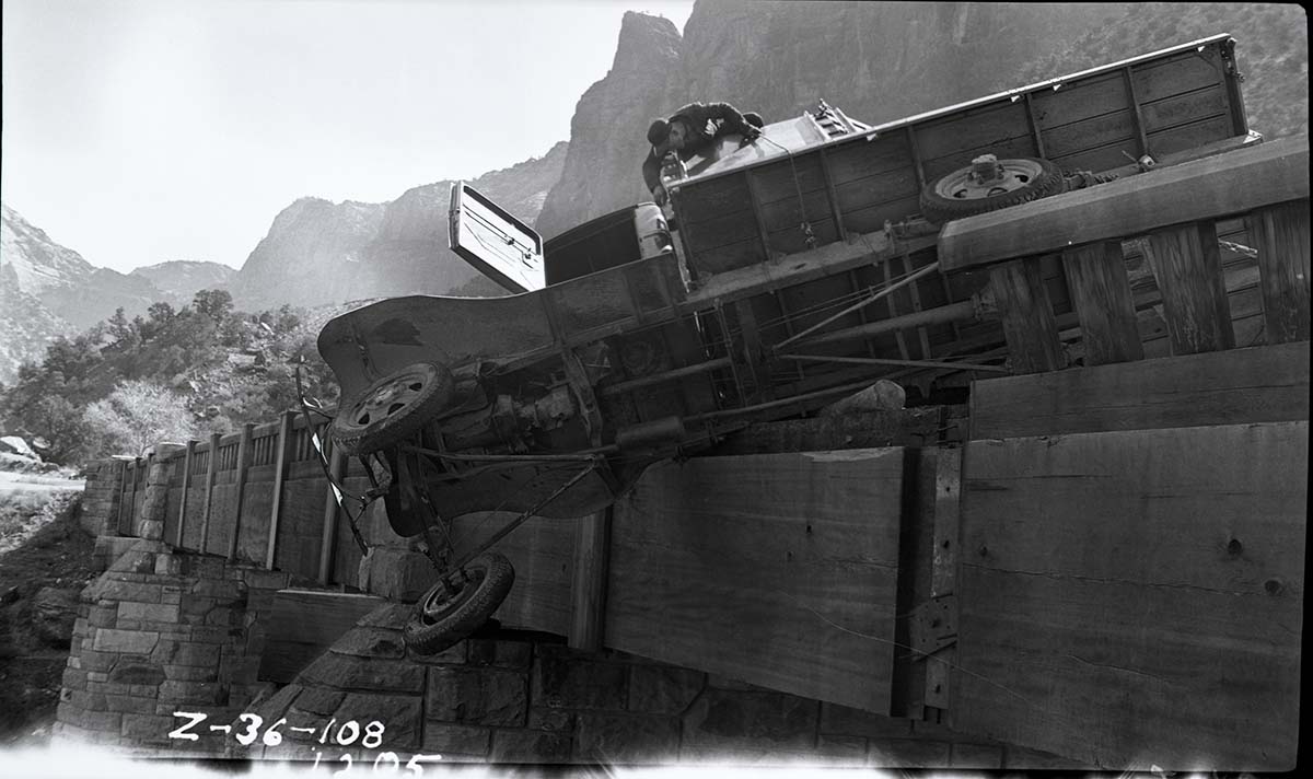 Vehicle accident on the Virgin River bridge of the Zion-Mt. Carmel Highway. View of a privately-owned truck turned on its side and resting on the bridge abutment.