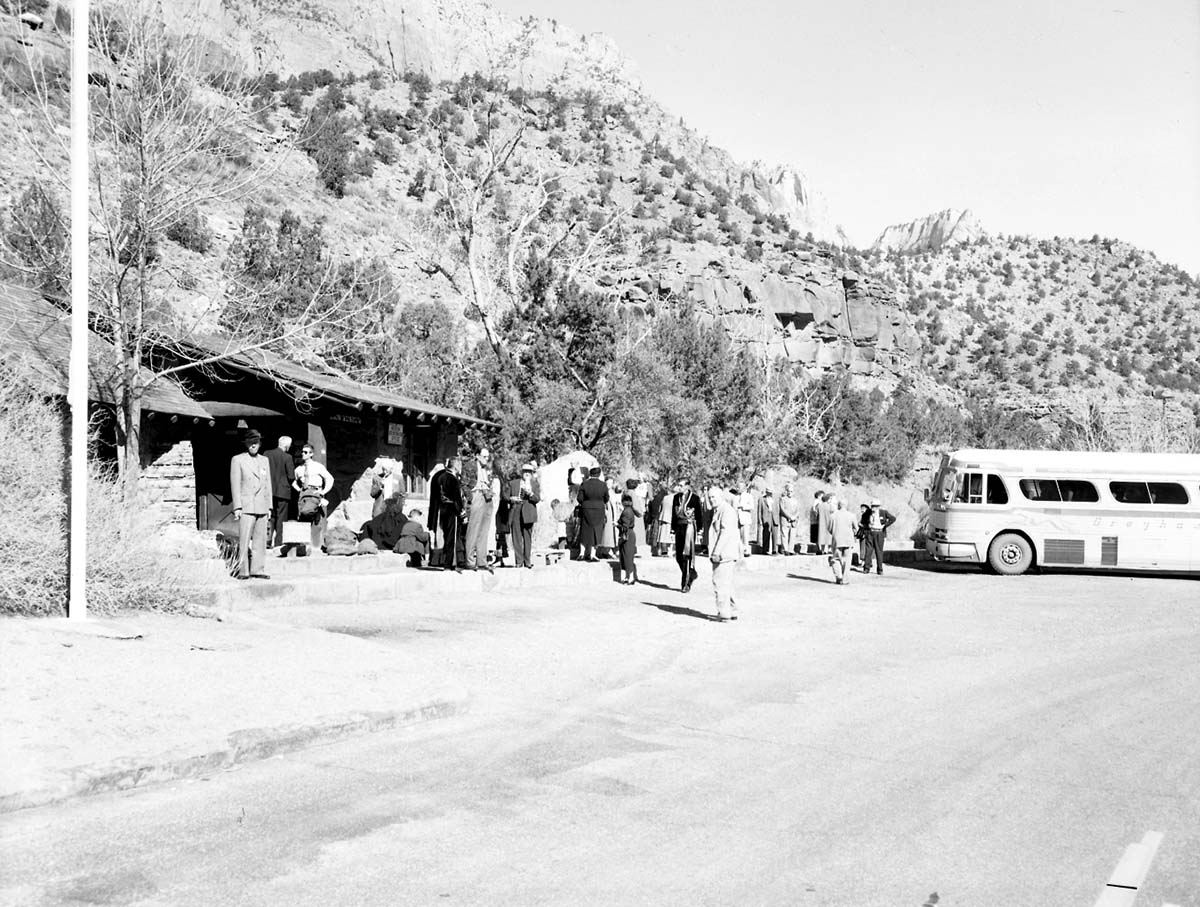 Visitors on Greyhound bus tour standing in front of Zion Museum. [Some men in traditional Spanish costumes?]