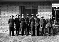 Rangers in uniform standing with Rudy Lueck (third from left) and Carl E. Jepson (second from right) outside Mission 66 Visitor Center and Museum and headquarters. Superintendent Warren F. Hamilton at far right.