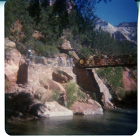 Men working on trail by the new Grotto footbridge. Overview of stone abutment for bridge and trail along Virgin River.