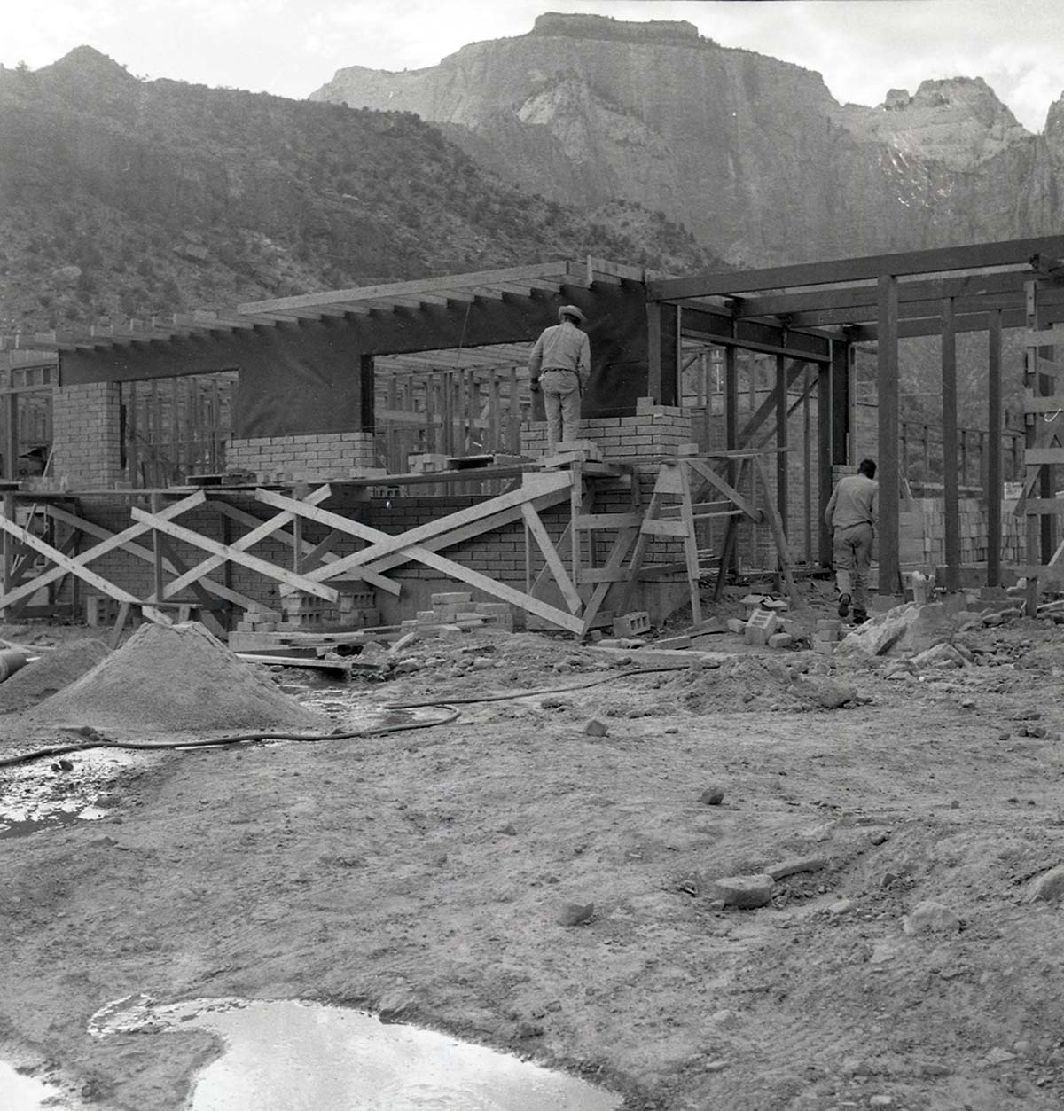 Two workers 'laying up' split blocks for visitor center wall during the Mission 66 Visitor Center and Museum construction.