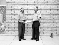 Superintendent Oberhansley presenting award for meritorious service to Dewey Excell upon his retirement, in front of Mission 66 Visitor Center and Museum.