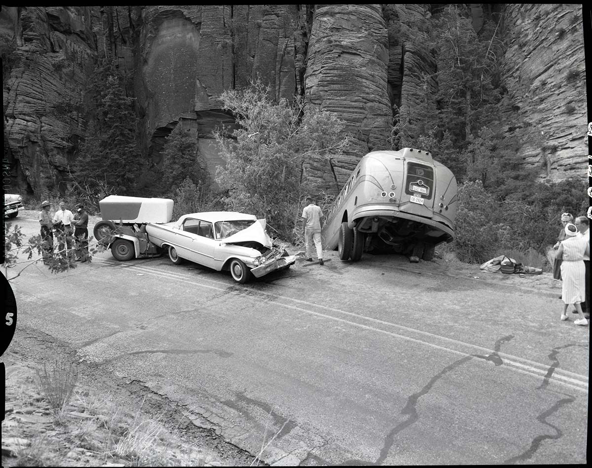 Collision between private car (Ford) towing U-Haul trailer and (Utah Parks Company) bus. Showing relation of car and bus, car coming down canyon, bus going up.