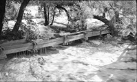 Flood damage to flume of the irrigation ditch at the Oak Creek bridge. Flume was completely removed in a later flood. Flood in progress.