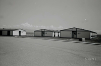 Barracks and parking area. Building numbers 57, 58, and 59. Mountains in background. [Image possibly for comparative housing study]