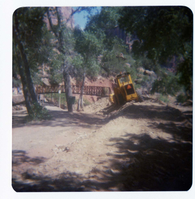 Backhoe moves fill dirt for trail after the placement of the new Grotto footbridge.