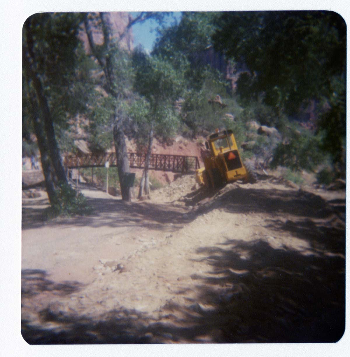Backhoe moves fill dirt for trail after the placement of the new Grotto footbridge.