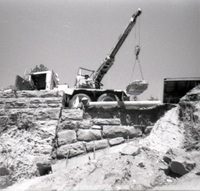 Man operating a crane lifting a rock during the retaining wall repairs along the East Rim road.