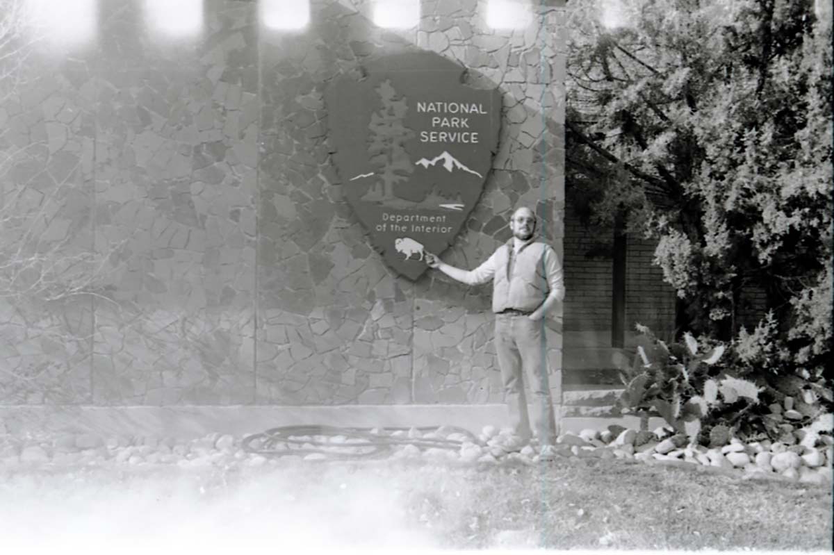 Man with beard pointing to National Park Service arrowhead.