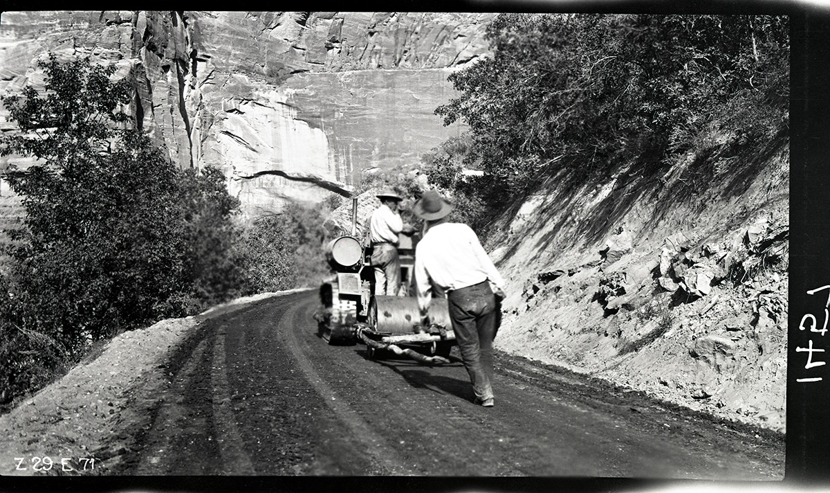 Workers rolling the new experimental pavement on the floor of the valley road.