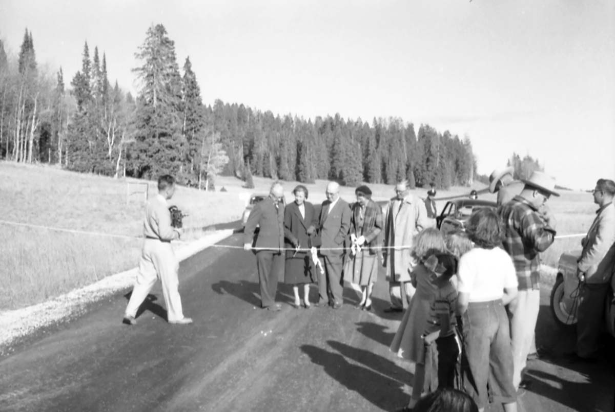 Dedication of Utah State Route 14 approach road. Mrs. Paul R. Franke (Zion and Bryce Canyon Superintendent) and Mrs. Beal cutting ribbon across road as photographer takes pictures.
