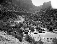 Oak Creek bridge and view of canyon- group of 75 motorhomes in caravan called the Fireballers, preparing to drive through tunnel. Park administration buildings in foreground.