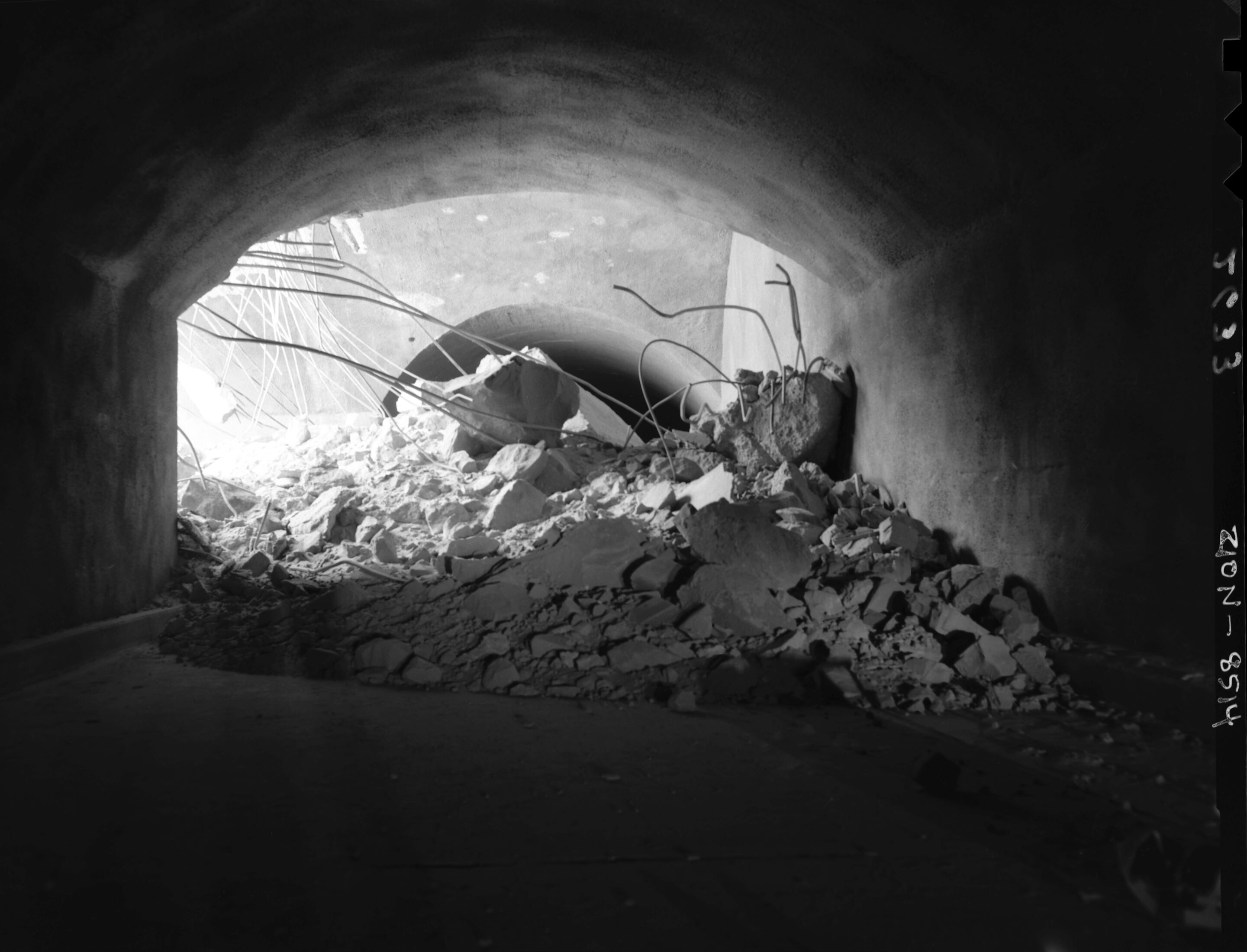 Rock fall behind Chief Ranger Fred Brueck's residence. Image shows house, rock, ranger, and woman sitting by rock fall depression.