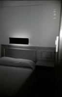 Bed and headboard in barracks. [Image possibly for comparative housing study]