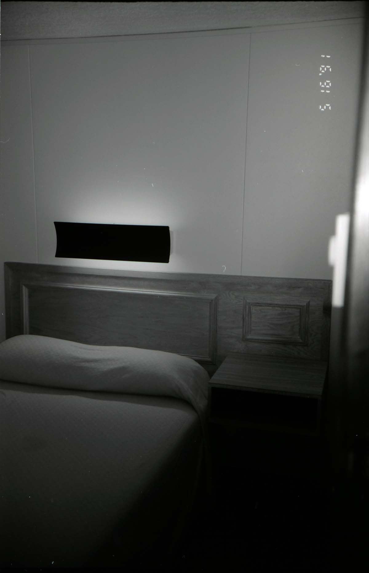 Bed and headboard in barracks. [Image possibly for comparative housing study]