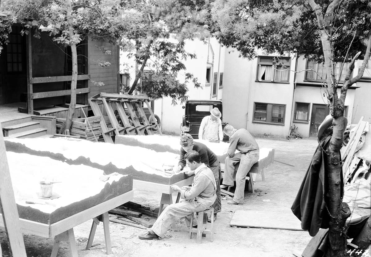 State Emergency Relief Administration (SERA) and Civilian Conservation Corps (CCC) workers outdoors 'pointing up' relief maps of Zion and other parks.