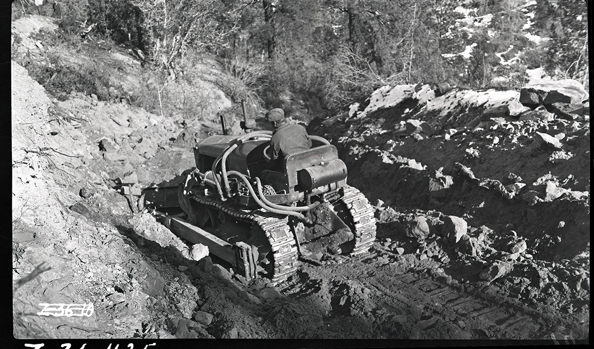East Rim Trail construction, view of man on a bulldozer moving earth along the route of the trail.
