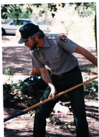 NPS employee picking up litter in campground area.