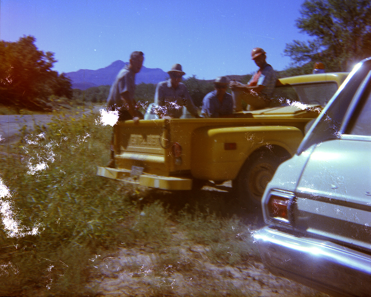 Men taking a break in the bed of a pick up truck during road construction.