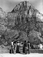Victor L. Jackson, Chief Park Naturalist and 1982 Freeman Tilden Award winner for outstanding interpreter of the year. Victor speaking to a group of visitors on the front patio of the Mission 66 Visitor Center and Museum, Bridge Mountain in the background.