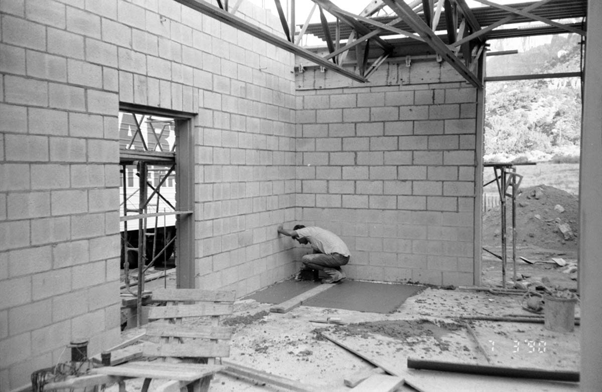 Man leveling cement in corner during construction of headquarters addition.