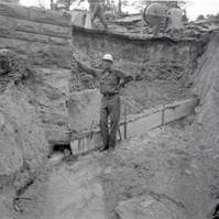 Man resting against retaining wall during repairs along East Rim road.