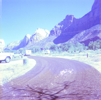 Cars driving along a turn in the road with Zion landscape in the background during chipsealing of the roads.