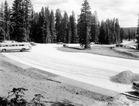 Cars in the partially constructed parking area at Point Supreme. Utah Parks Company bus parked at left, construction equipment at right. View back towards museum.