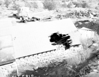 The rock slide of November 23, 1947, utility yard (Oak Creek maintenance area), large boulder on crushed truck. Woman and three children looking at the damage.