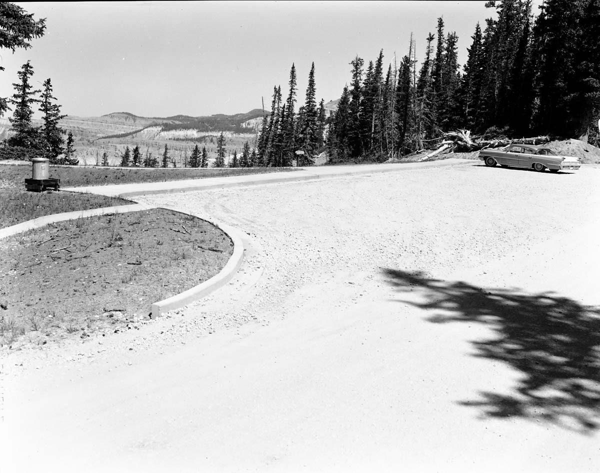 Car parked at the parking area at 'Sunset View' overlook on rim road (desert view) after completion of construction. Trash can at edge of walkway. Record of project completion.