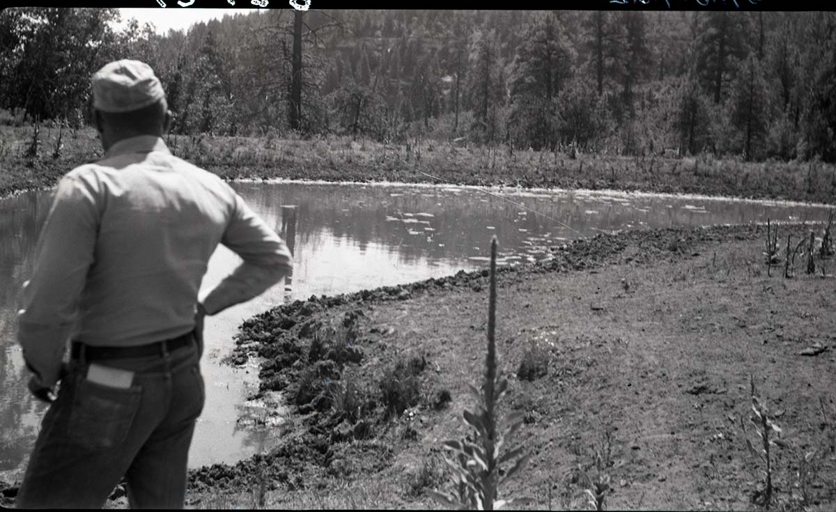 Earth tank, Potato Hollow, man standing at edge of filled tank.