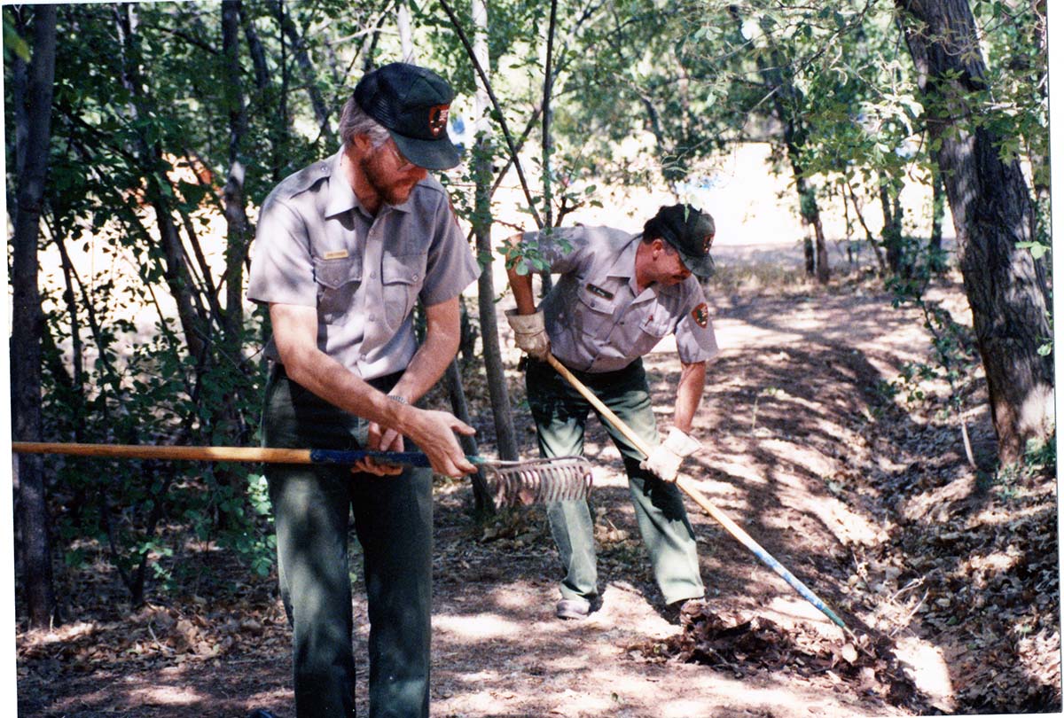 NPS employee picking up litter in campground area.