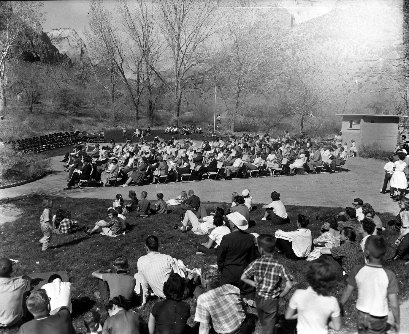 Visitors on benches and sitting on the lawn at the Zion amphitheater for the Easter festival.