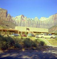 Headquarters building with vehicles parked in the parking lot and a backdrop of The Altar of Sacrifice, Sundial, and West Temple.