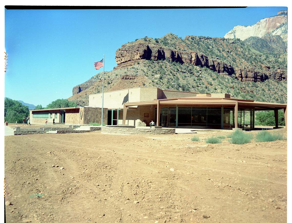 Exterior of old Mission 66 Visitor Center and Museum, with dirt lot surrounding building.