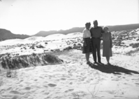 Man and two women standing together on sand at Coral Pink Sand Dunes near Kanab, Utah.