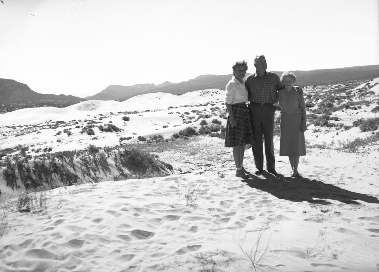 Man and two women standing together on sand at Coral Pink Sand Dunes near Kanab, Utah.