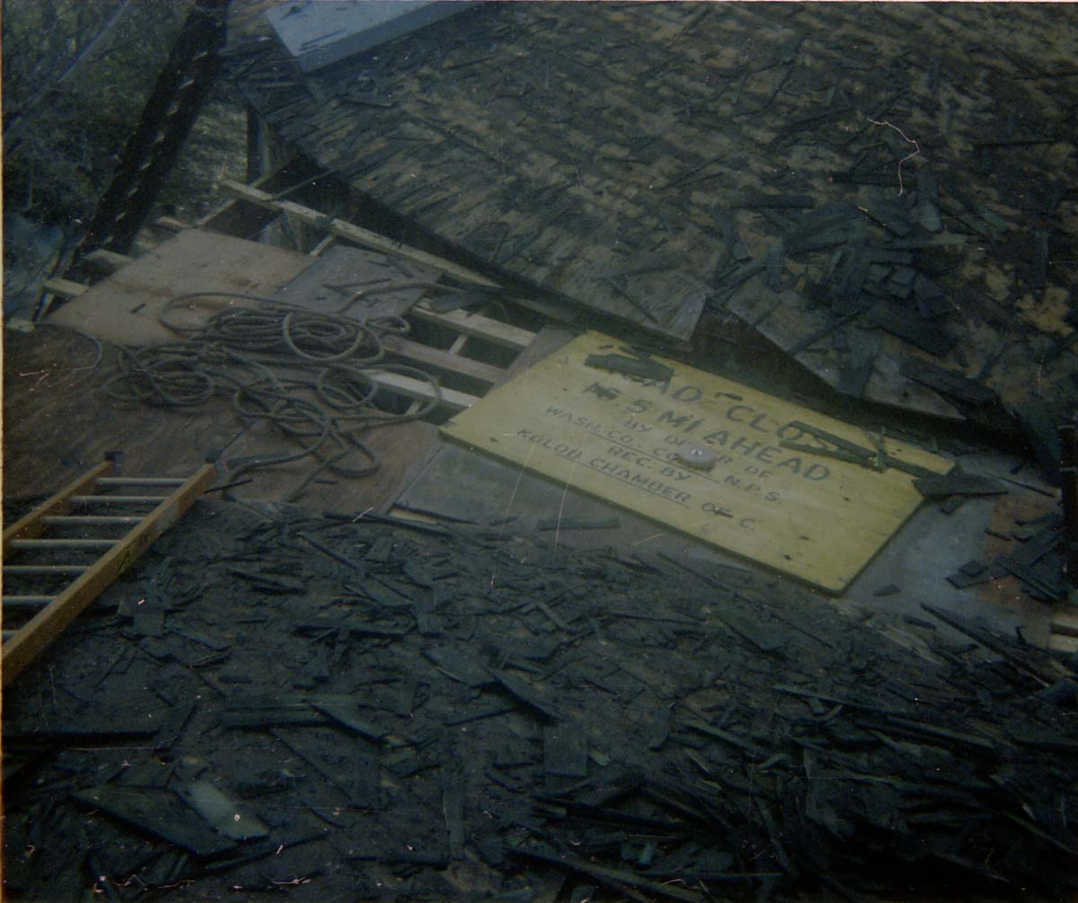 Pile of old shingles removed from water tank during reroofing project, old road sign used as part of scaffolding.