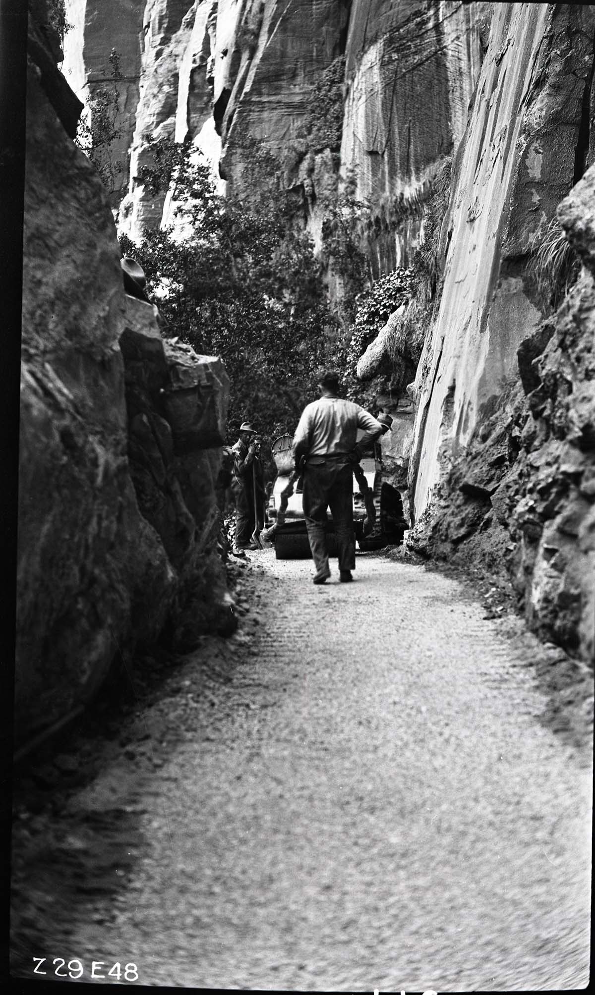 Narrows Trail construction with rolling finished, four workers take a break at a rock cut.
