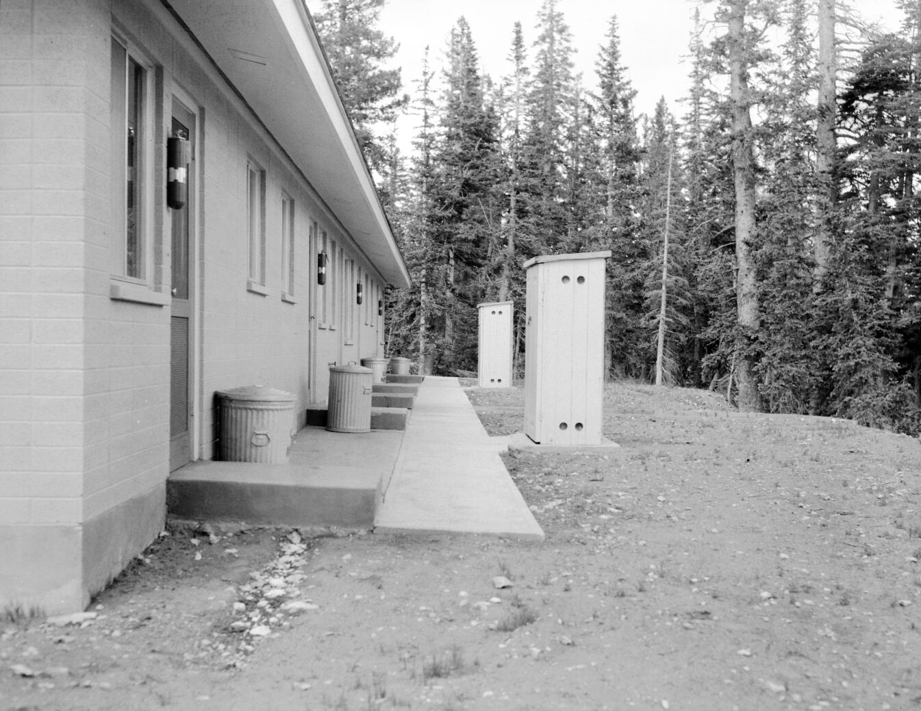 Backside of multiplex during landscaping in the residential area, fire extinguishers and trash cans flanking back doors.