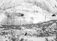 Damaged tractor/trailer truck in Oak Creek maintenance area. Damage caused by rock fall boulders, visible on top of trailer and several workers. [Original nitrate Negative Number 2194]