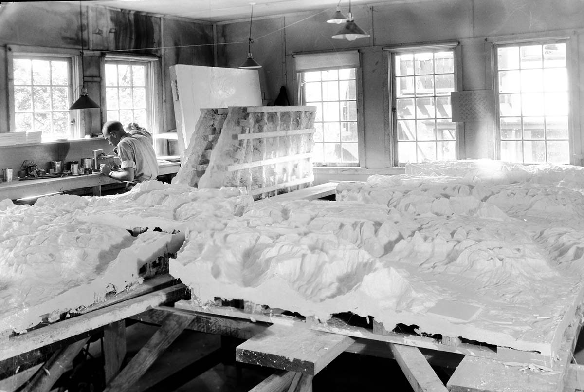 Worker in Western Museum Laboratory (WML) with park relief maps under construction.