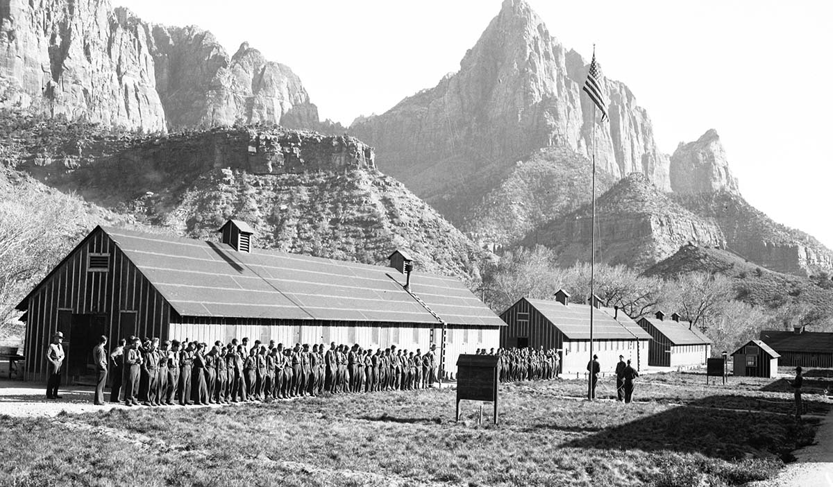 Personnel: 'Civilian Conservation Corps (CCC) boys' retreat at Camp NP-2, men in formation in front of barracks with the Watchman in background. Used for graphic in Zion Human History Museum.