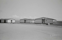 Barracks and parking area. Building numbers 57, 58, and 59. Mountains in background. [Image possibly for comparative housing study]