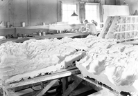 View of interior of Civil Works Administration (CWA) College Avenue laboratory showing plaster cast of Zion relief map. Background: interior of shop facility and worker.